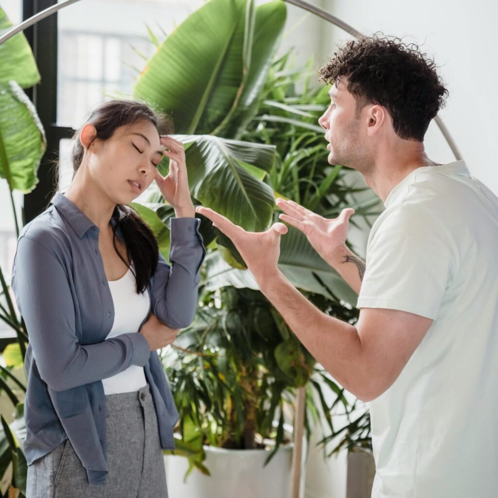 A man and woman having a heated argument indoors, surrounded by plants.